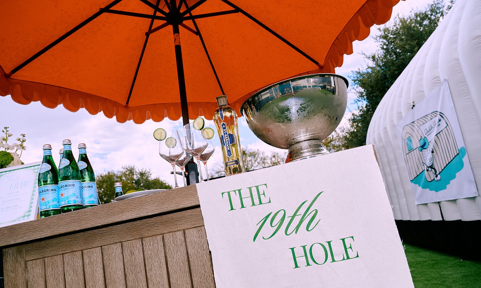 Cocktail bar in front of golf simulator. Sign that says "The 19th Hole"