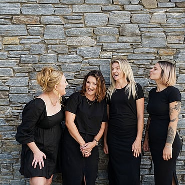 The Salon staff lined up outside The Salon laughing together.