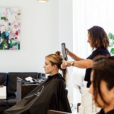 Elaine in the salon brush blowdrying a client's hair.