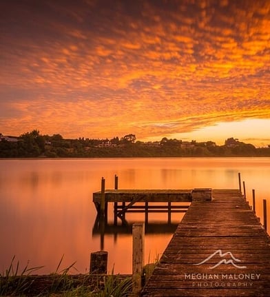 Timber jetty silhouetted against a fiery sunset sky near Cambridge