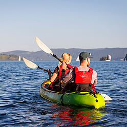 Couple kayaking on Rotorua Lake. Enjoying kayaking across peaceful waters, getting ready to explore the lakes glow worms in their natural habitat.