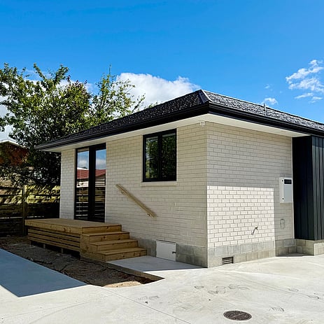 Image of a soft neutral stone small building with wooden step entrance on Clarkin Road. Built by Ardent Building Developments, Hamilton. Waikato, New Zealand.
