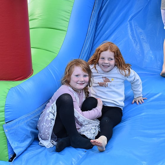 school holiday programme, two girls playing on a bouncy castle