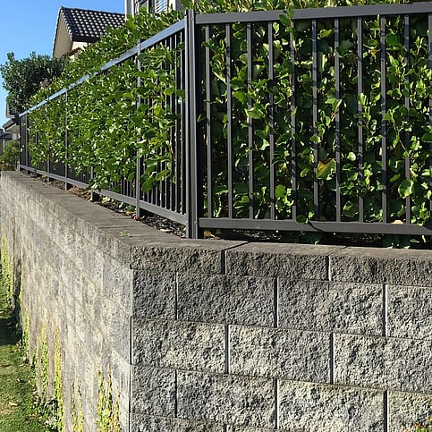 photo of a high wall, made safe with Moduline barrier fencing, with shrubs for extra beauty