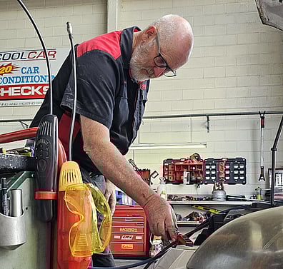 Technician checking car's condenser with leak detector device