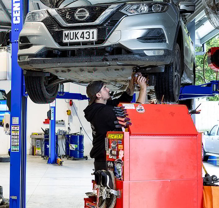 Man servicing a car, standing underneath it