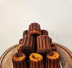 A pile of Caneles. caramelized outsides and fudgy centers.