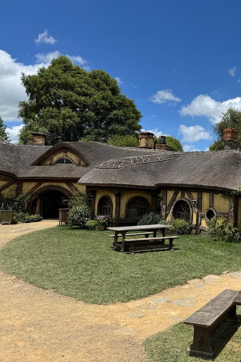 A hobbit house nestled in the green hills of Hobbiton, representing North Island&rsquo;s unique movie sets and lush landscapes.