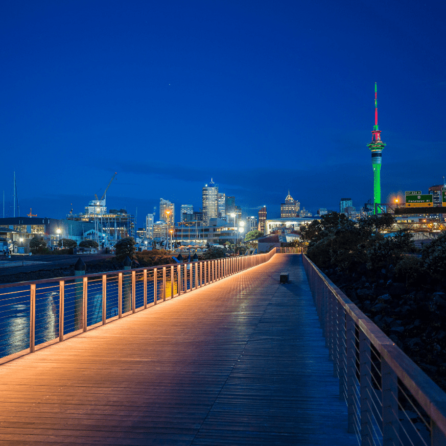 Evening view of a lit-up boardwalk with Sky Tower visible in the background