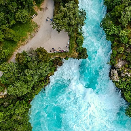 Aerial view of turquoise rapids at Huka Falls surrounded by native bush