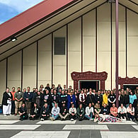 Group of people posing for photo outside of marae