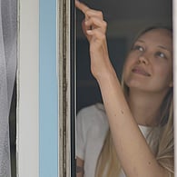 Woman pointing and looking at window frame