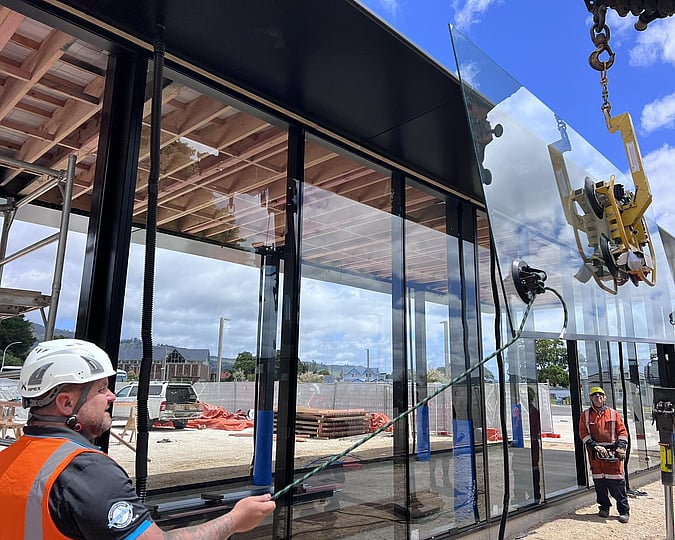 Workers from The Glass Guys installing large panels on glass on a large-scale commercial project in Rotorua