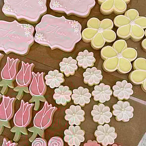 Gluten free pale pink meringues with striped chocolate detail raspberry dust sprinkles and gold balls two strawberries decorate the edge of the photo