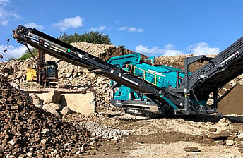 Powerscreen Warrior 1800 screening machine for hire, working in waste concrete recycling yard processing crushed concrete into grades