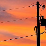Electricity power lines silhouetted against a colourful sunset sky