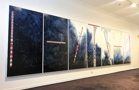 Large scale painting made up of seven panels in gallery space. Predominantly in shades of black and blue with highlights in red and white te reo text and designs