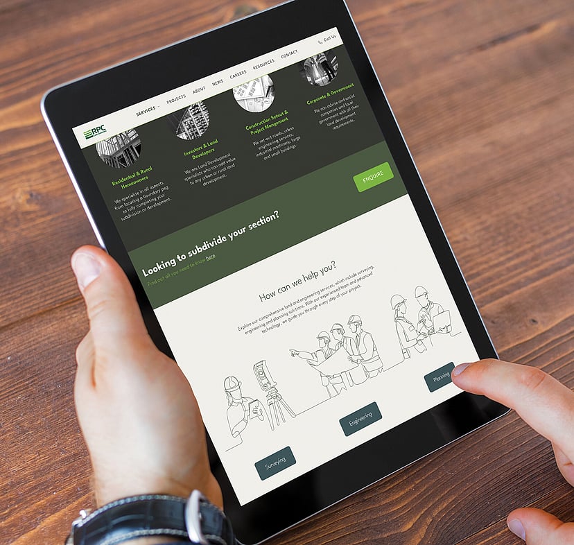 A person holds a tablet displaying the RPC website, showing services like surveying and planning, with a clean design and green accents