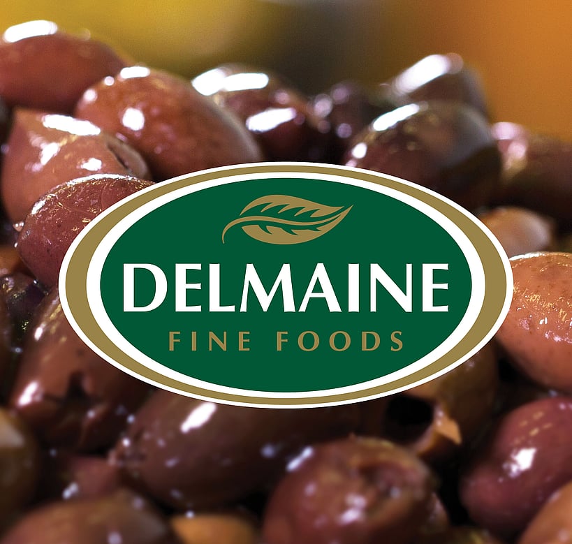 A green and gold Delmaine logo design over a close up of Spanish olives.