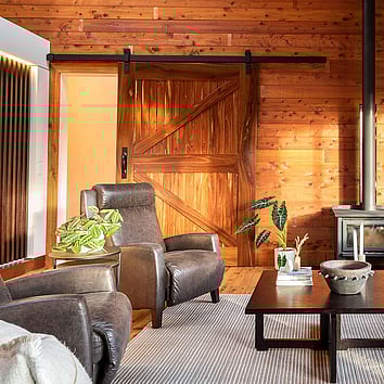 Timber barn door and brown leather armchairs