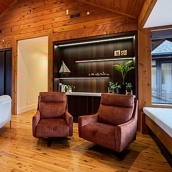 two arm chairs in a home with timber floor and walls