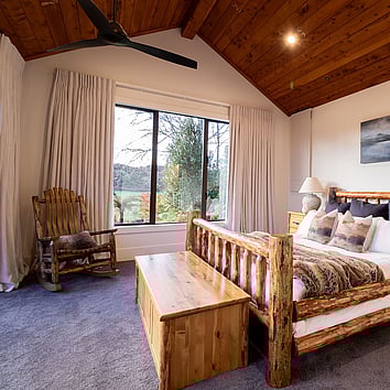 Master bedroom with rustic timber bed frame and timber rocking chair. 