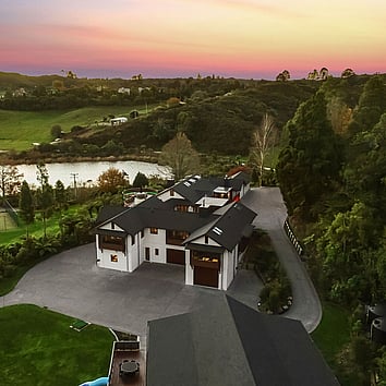 Arial view of large family home surrounded by New Zealand native bush and a beautiful sunset. 