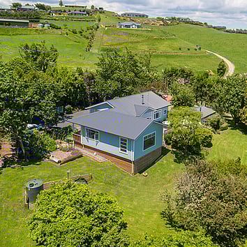 traditional light blue weatherboard home in a rural New Zealand setting. 