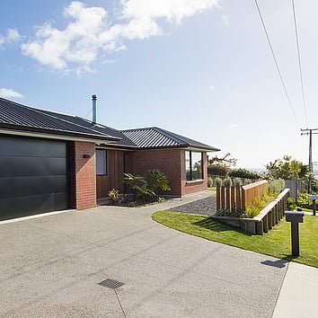 Red Brick home with timber fence and concrete driveway.