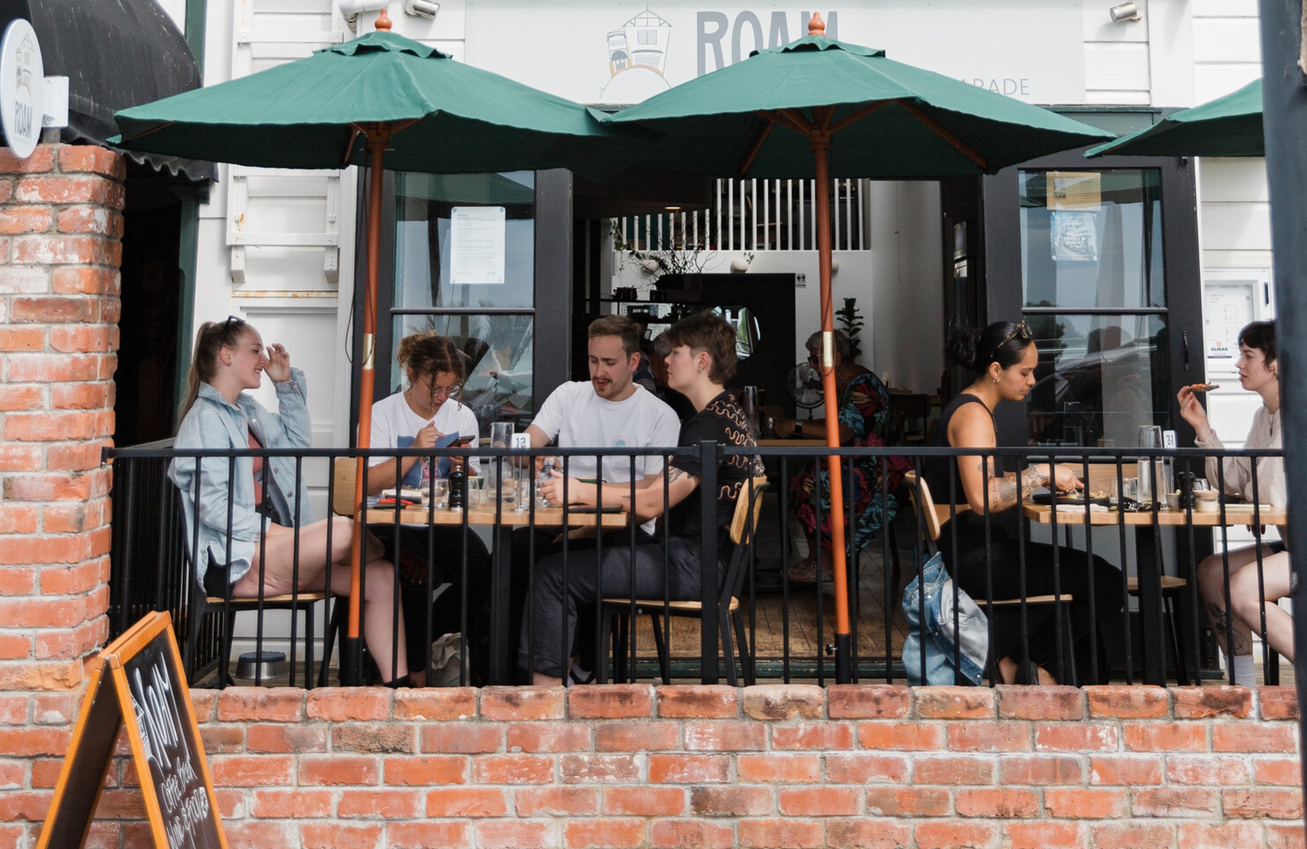 Image of people enjoying great coffee, wine, bear and food at ROAM Marine Parade cafe in Napier, Hawkes Bay. New Zealand.