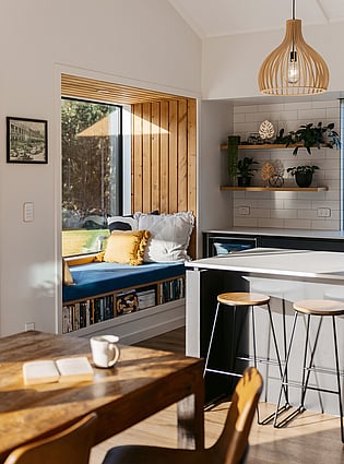   This image shows the newly built window seat next to the kitchen. The dining table is in the foreground with a mug of coffee on it. 