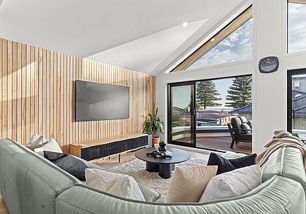 An after image of the living space renovation with timber walls, new joinery and large window looking out towards mount maunganui beach. 
