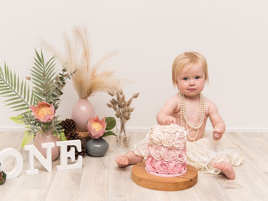 Tauranga Photographer.  Jackie O'Photography.  Cakesmash Photographer Tauranga.  Girl with pink cake and flowers for 1st birthday photoshoot.