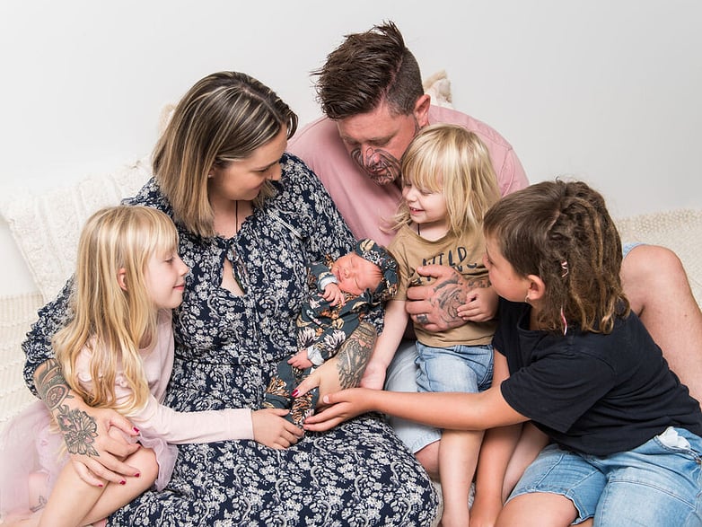 family of six cuddling newborn baby 