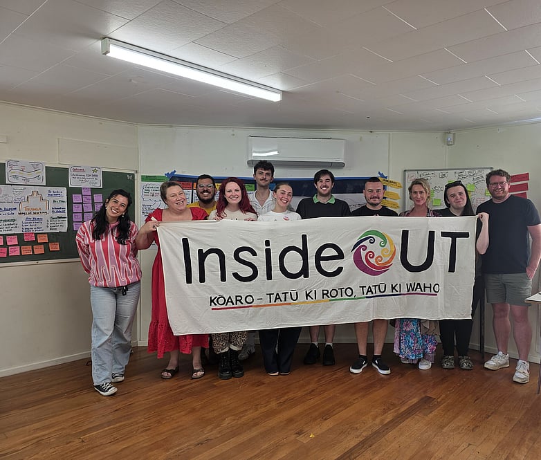 Group holding an InsideOUT banner, standing together after a workshop session.