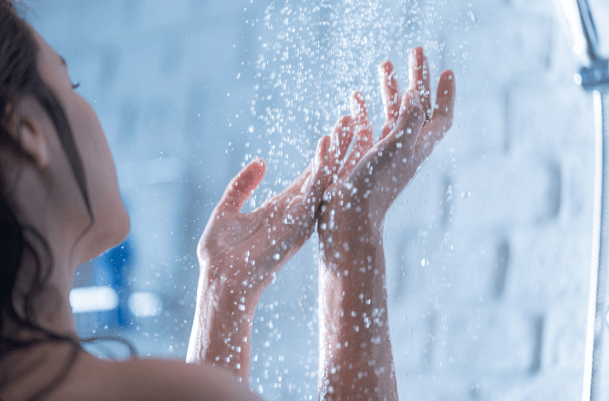 Woman enjoying a hot shower heated by a hot water heat pump