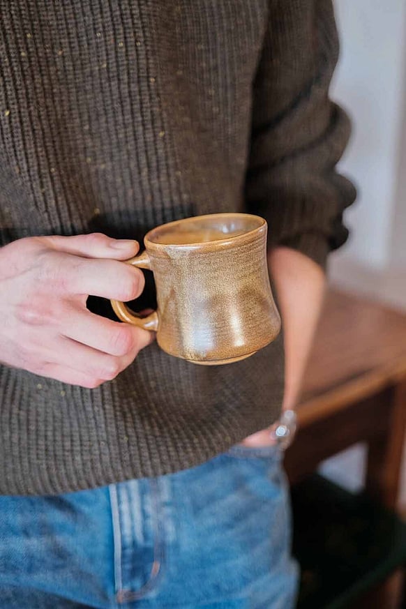Person holding coffee in a vintage cup, standing in Auckland cafe
