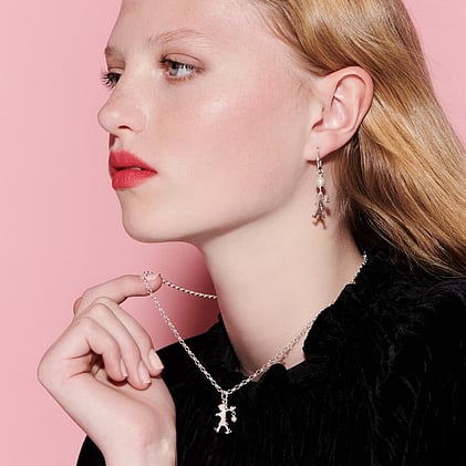 Young woman wearing Karen Walker runaway girl pendant and earrings.