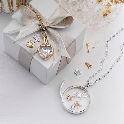Jewellery box and ribbon with gold heart locket, silver circle pendant and charms.