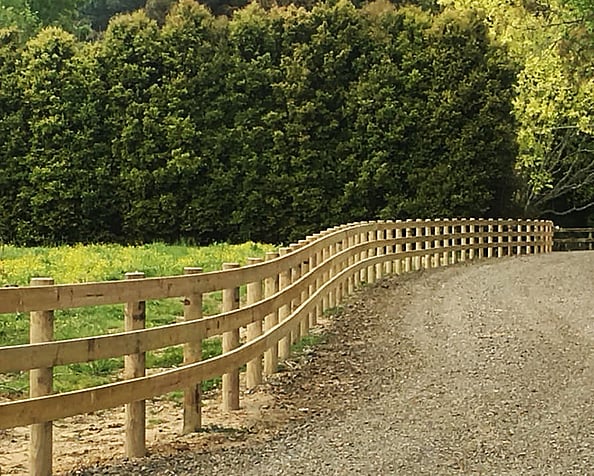 Post and rail fencing along gravel farm track. Habraken Fencing Ltd, Auckland & Waikato.