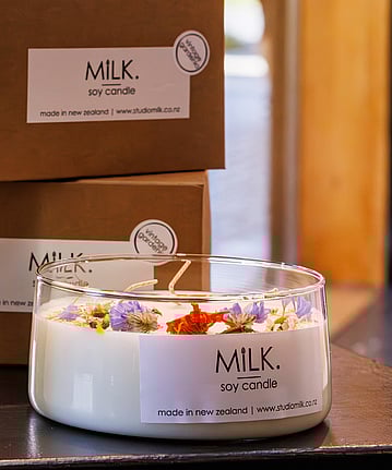 A creamy white candle in a clear glass dish.