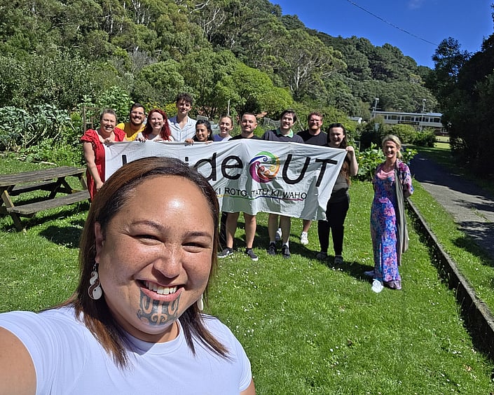 Group outdoors holding a banner, smiling together after a workshop.