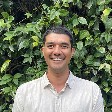 Shane smiling at camera, greenery behind him