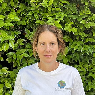Angela smiling at camera, greenery behind him