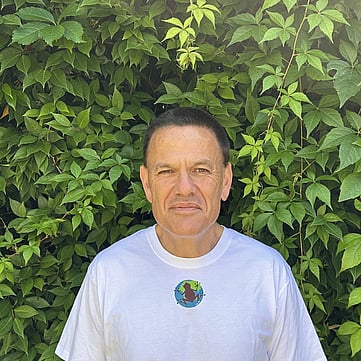 Terry smiling at camera, greenery behind him