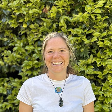 Amy smiling at camera, greenery behind him