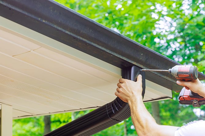 man installing downpipe for spouting