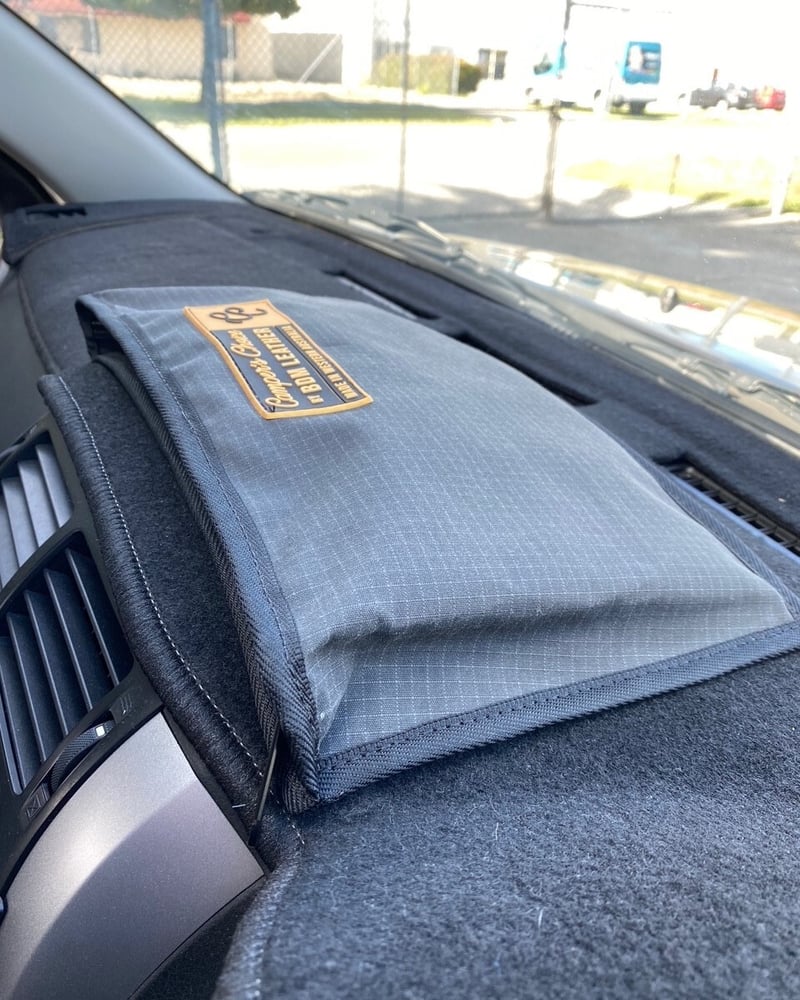 Grey ripstop canvas dash organiser with clear panel sitting on a car dashboard