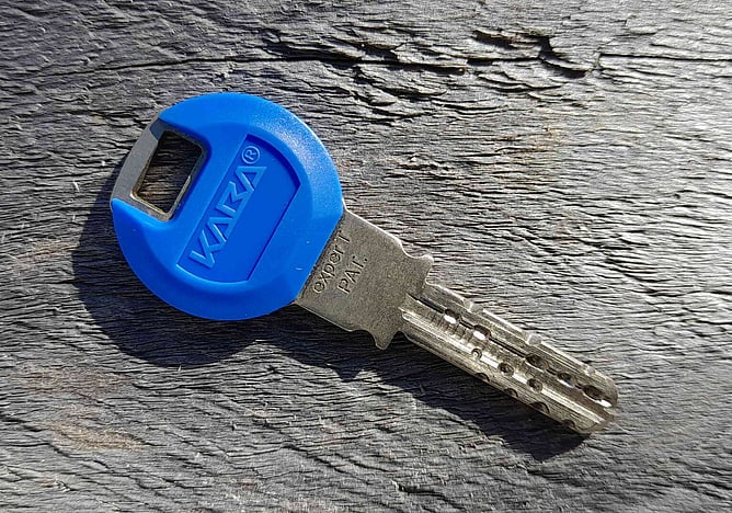 A photo of a blue Kaba high security key on a wood surface