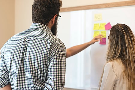 Two people collaborating at a whiteboard, representing GGA's commitment to best practice governance